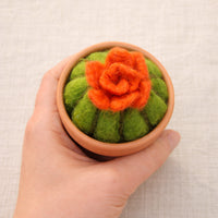 Needle felted cactus with orange flower in miniature terracotta pot held in palm