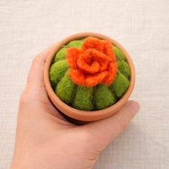 Needle felted cactus with orange flower in miniature terracotta pot held in palm