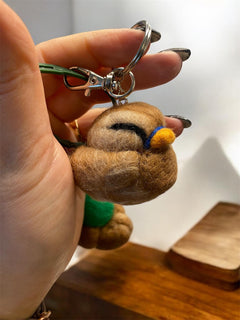 Needle felted duck keychain pair arranged on cream surface