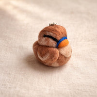 Needle felted robin keychain with brown and tan wool body, blue eye mask, and orange breast detail