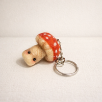 Needle felted toadstool keychain held in hand showing size